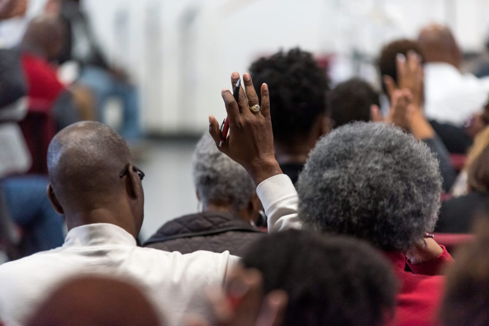 African American Man in a White Suit at Church with His Hand Rai